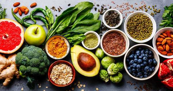 Colorful vegan ingredients including vegetables, fruits, nuts, and seeds arranged beautifully