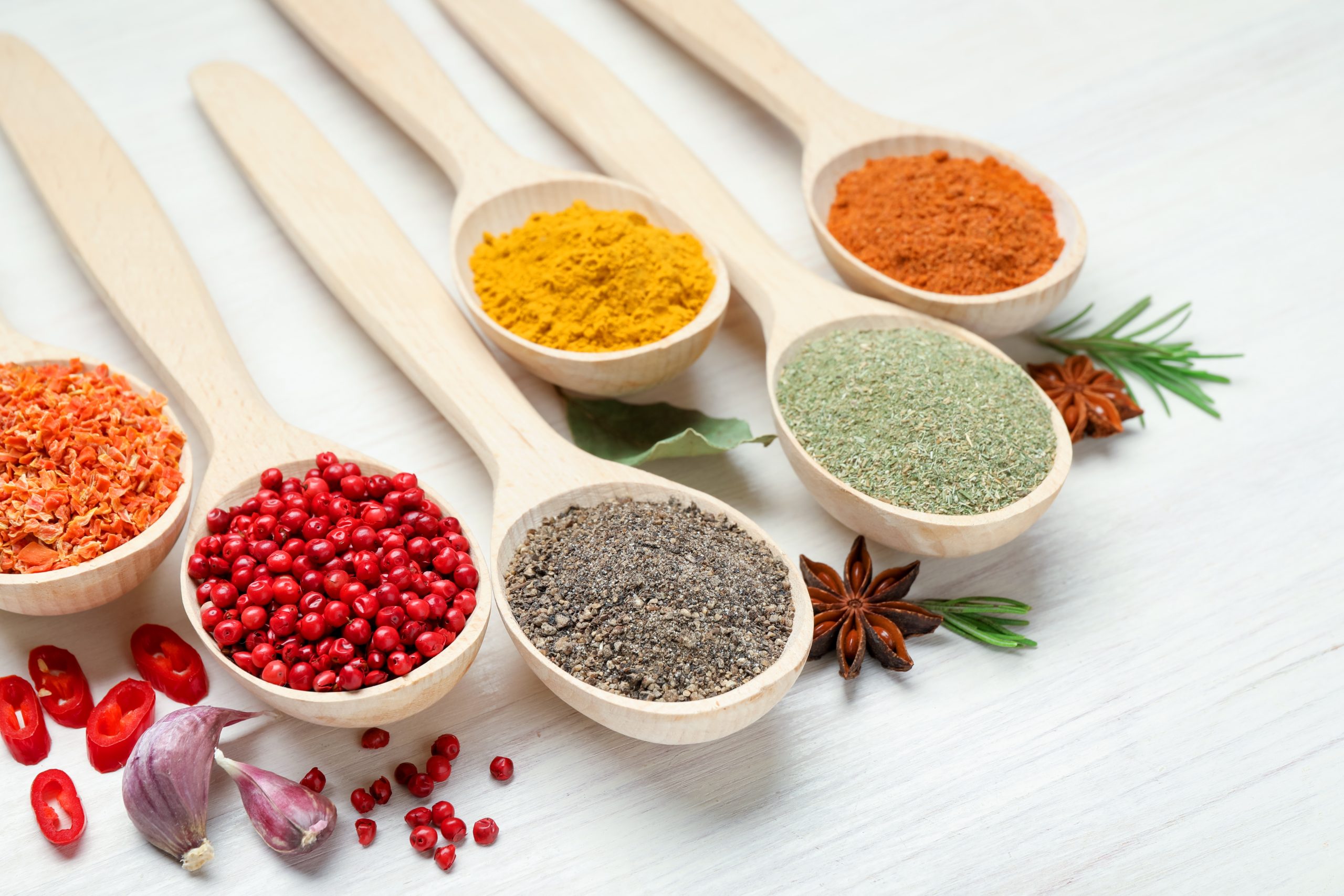 Colorful healthy herbs and spices in wooden spoons for natural gut wellness