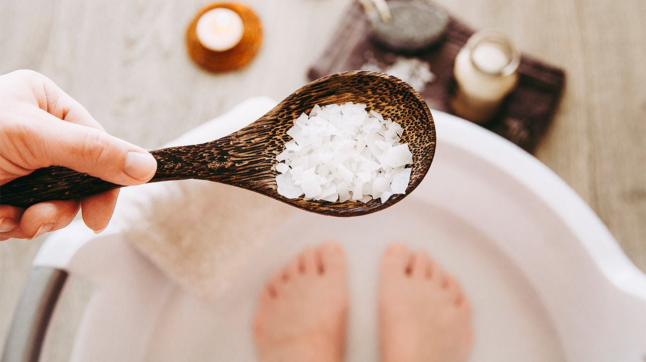 Person preparing Epsom salt foot soak for tired leg relief at home