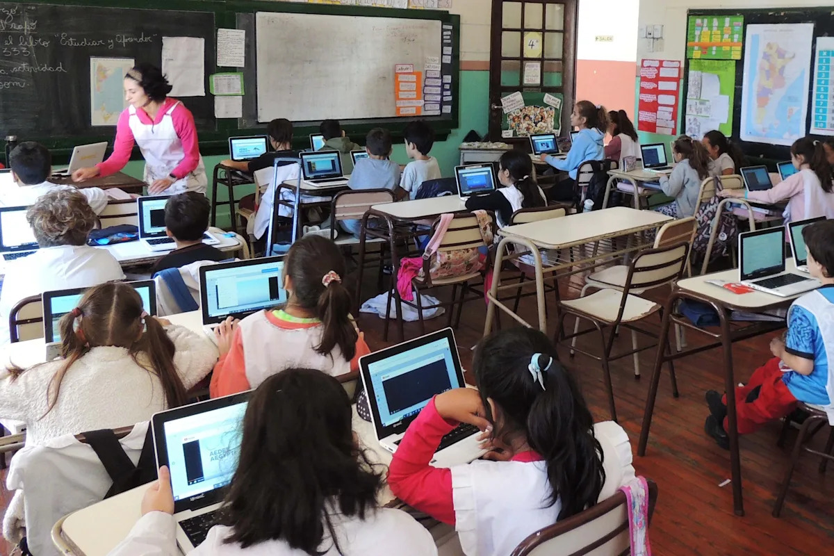 Estudiantes de secundaria en Colombia trabajando en equipo en un aula con tabletas y libros de texto