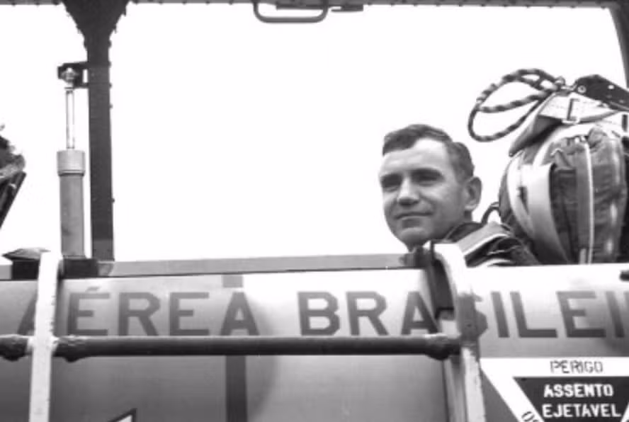Foto histórica em preto e branco do engenheiro Ozires Silva, fundador da Embraer, dentro de cockpit de aeronave da Força Aérea Brasileira