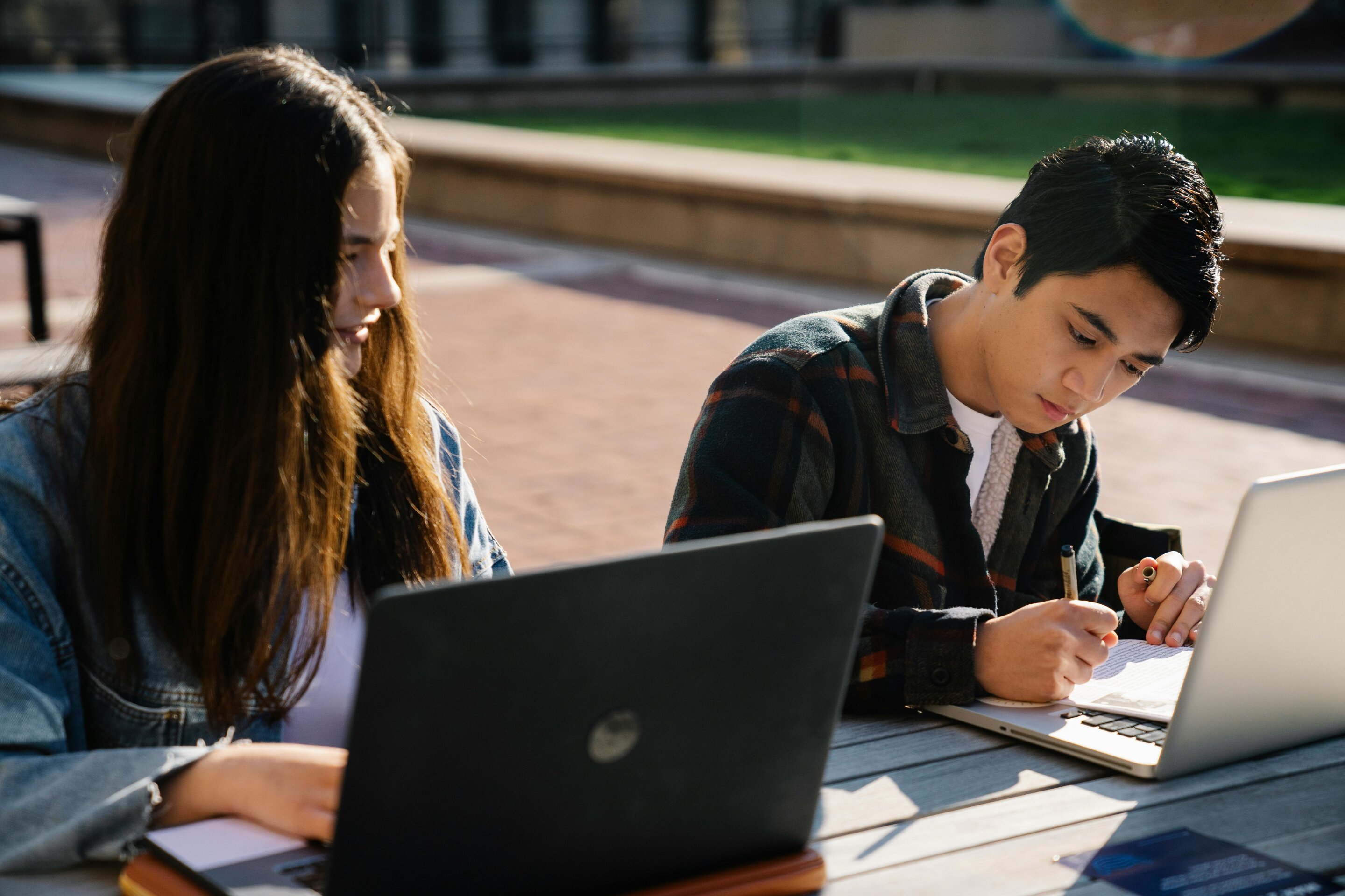 College students studying together outdoors with laptops