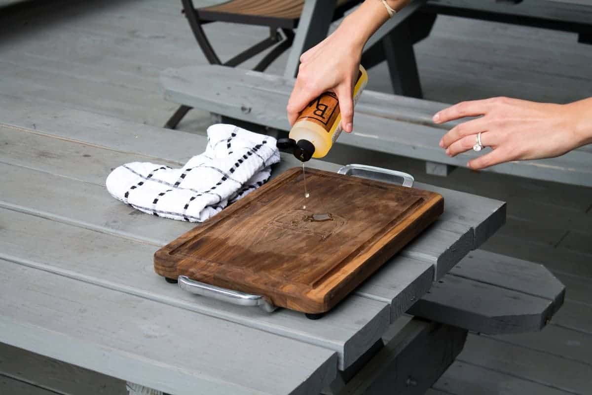 Applying food-grade mineral oil to a restored wooden cutting board using a clean cloth after sanding