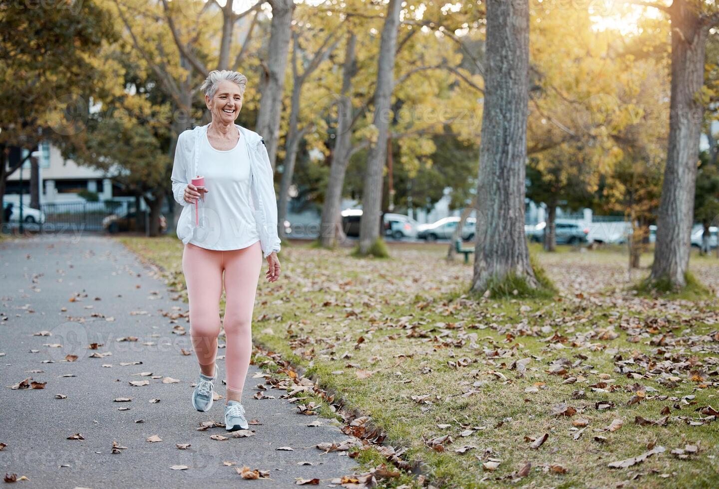 Senior woman walking outdoors in park for morning exercise and wellness