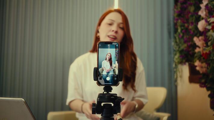 Person recording video with smartphone on tripod indoors