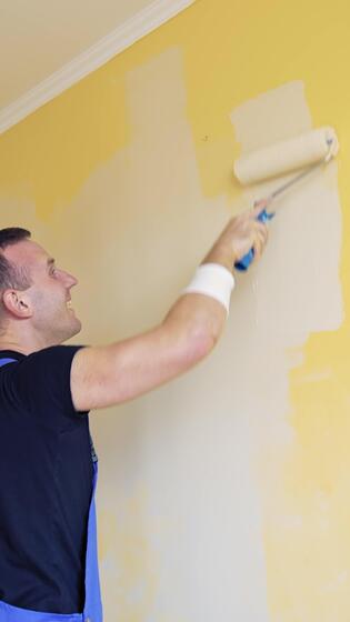 Painter painting wall with roller