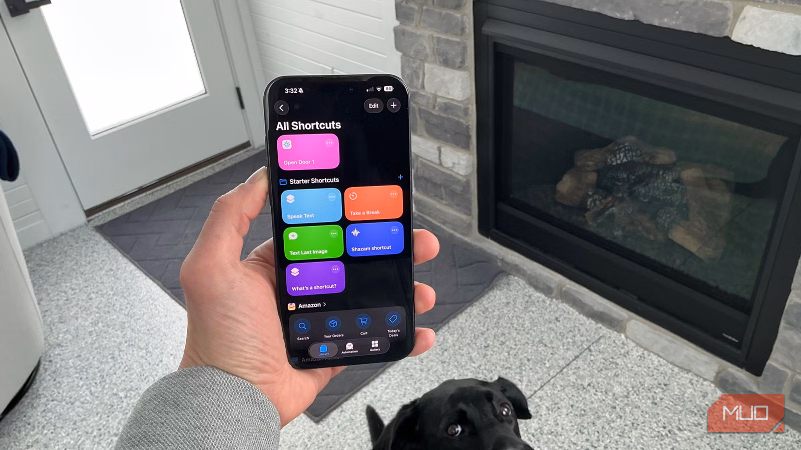 Hand holding iPhone displaying colorful Shortcuts app automation screen indoors