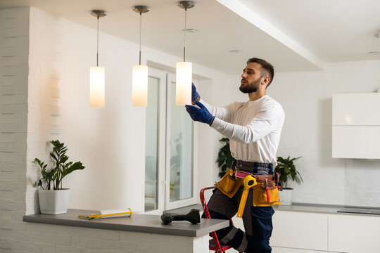 Electrician installing light fixture