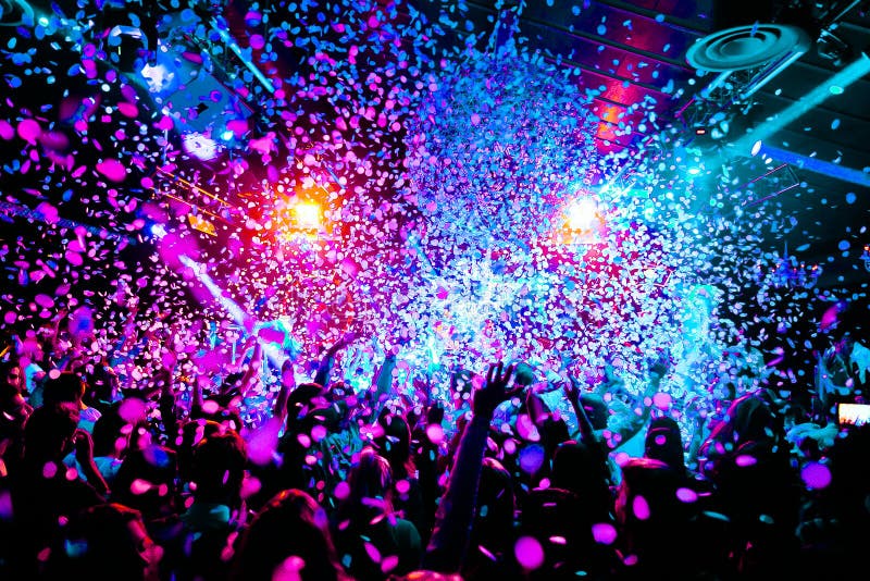 Concert crowd celebrating under vibrant stage lights and confetti