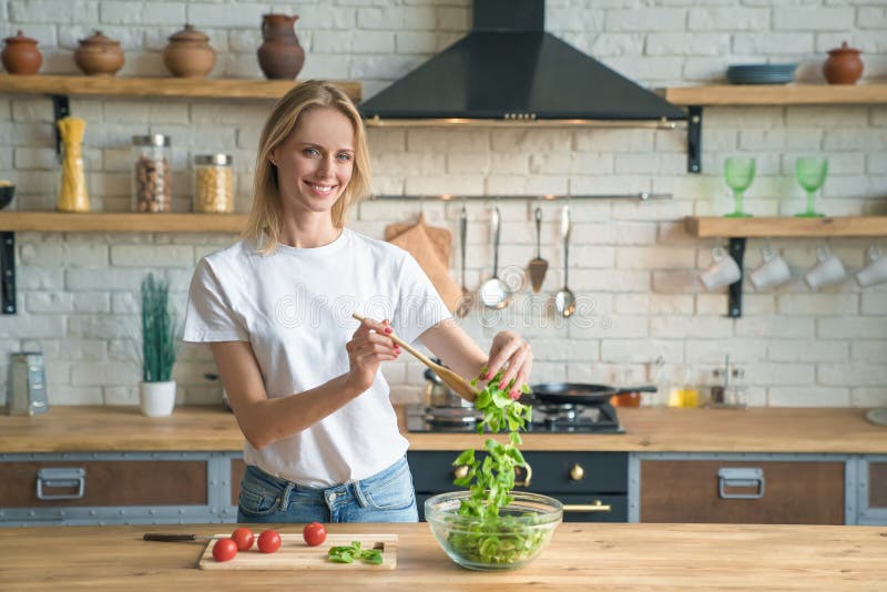Woman preparing a fresh green salad in a bright modern kitchen