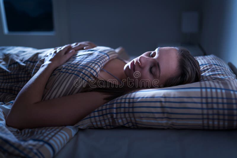 Woman sleeping peacefully in dark bedroom