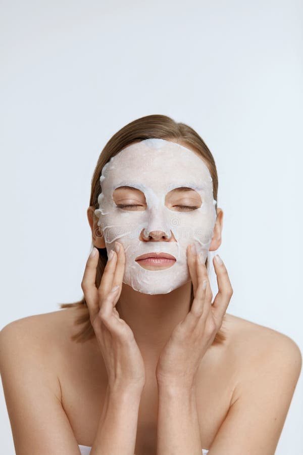 Woman relaxing with a white sheet mask on her face for spa care
