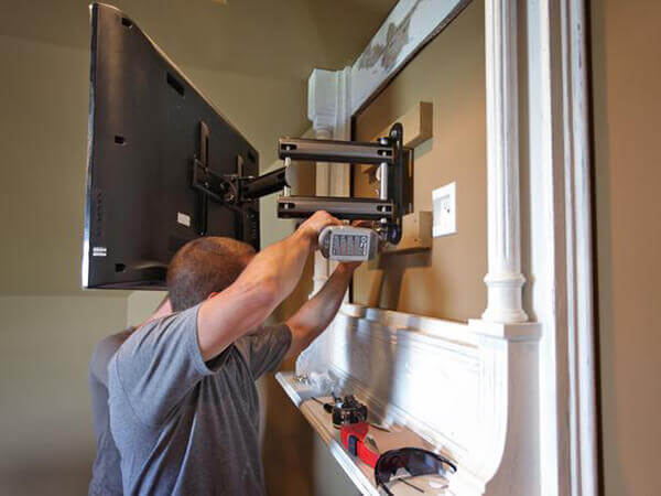 Technician mounting TV on wall