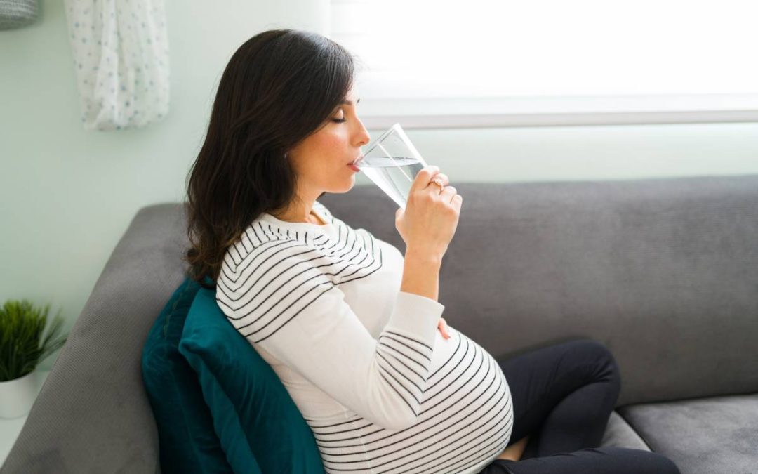 Pregnant woman drinking water for proper hydration during pregnancy