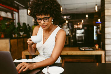 African woman entrepreneur focused on laptop at cafe