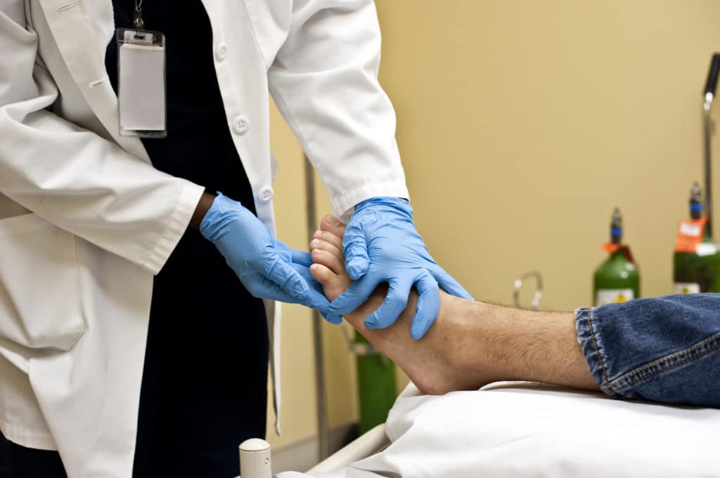 Podiatrist examining patient's foot in clinical setting