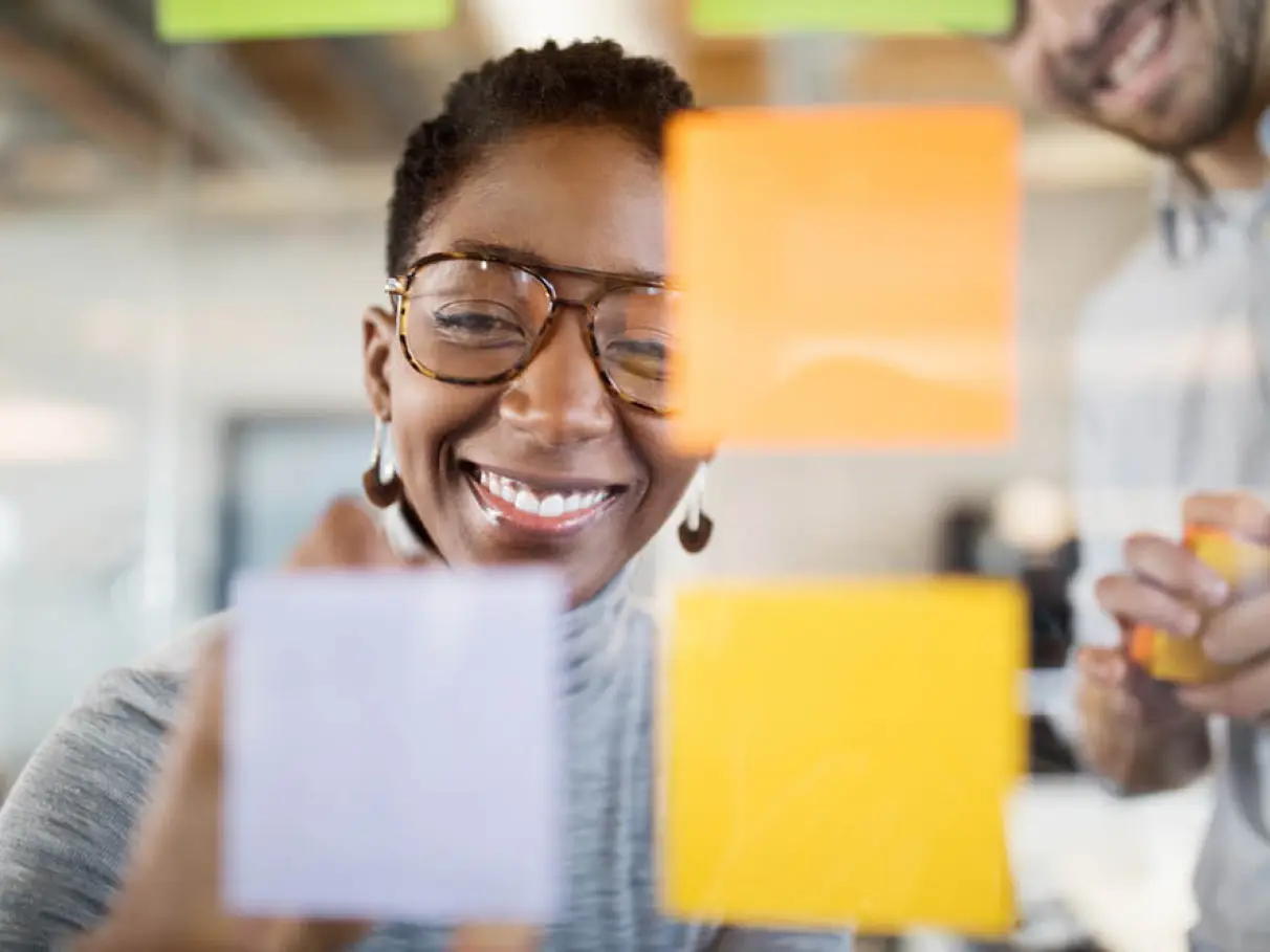 Mulher sorridente em ambiente de trabalho colaborativo, representando produtividade e bem-estar