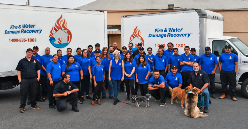 Large water damage restoration team posing with service vans, ready for nationwide emergency dispatch