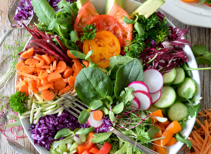 Colorful variety of leafy greens, vegetables, and berries arranged in a bowl for brain health nutrition