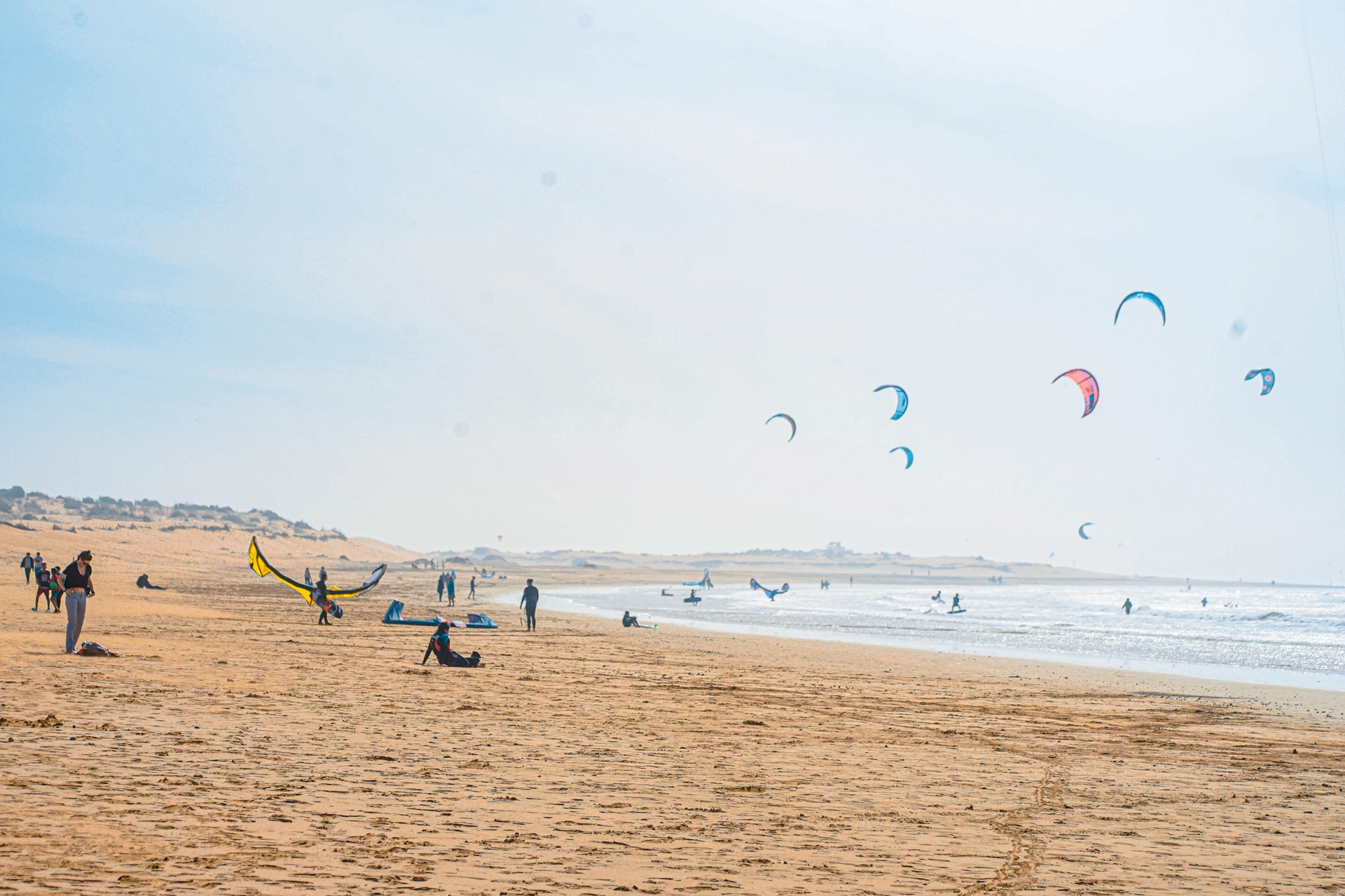 Plage d'Essaouira avec kitesurfeurs et dunes en arrière-plan