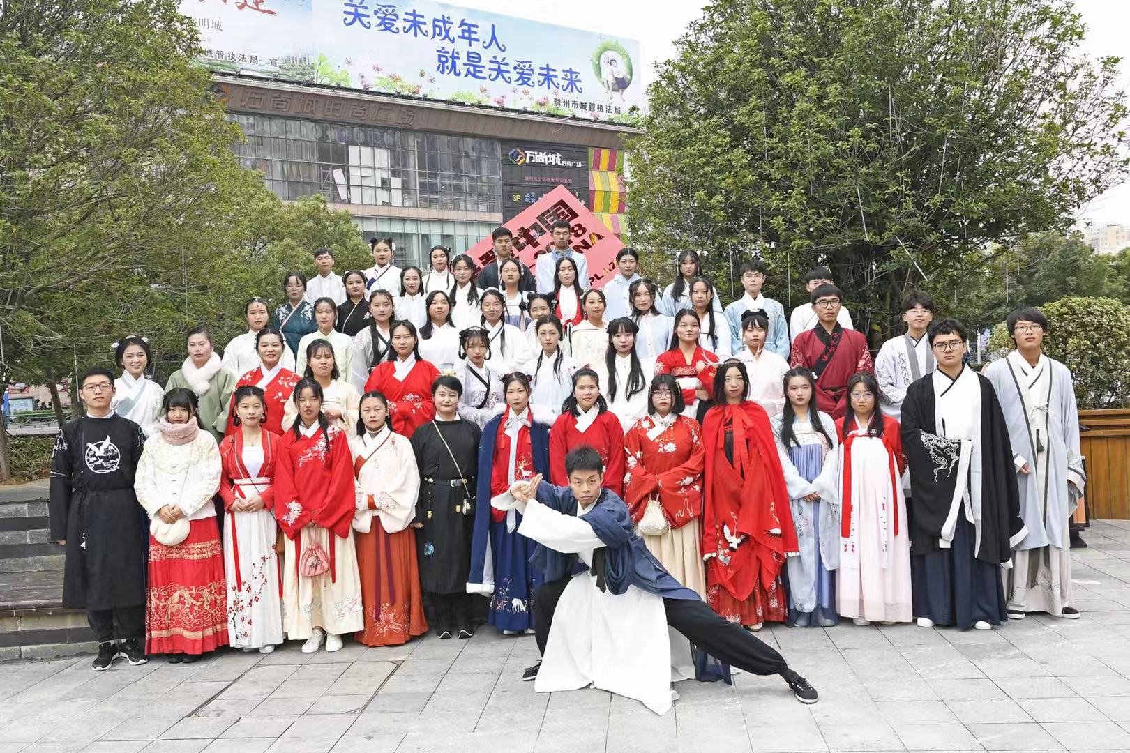 一群年轻人穿着汉服在传统建筑前展示文化自信