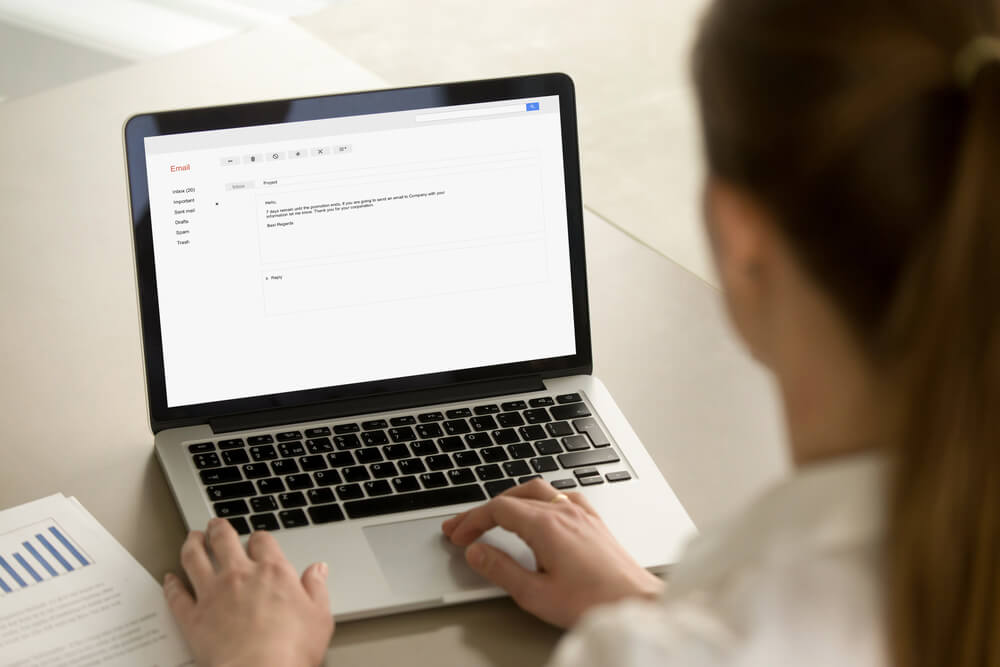 B2B professional reading email on laptop in office environment