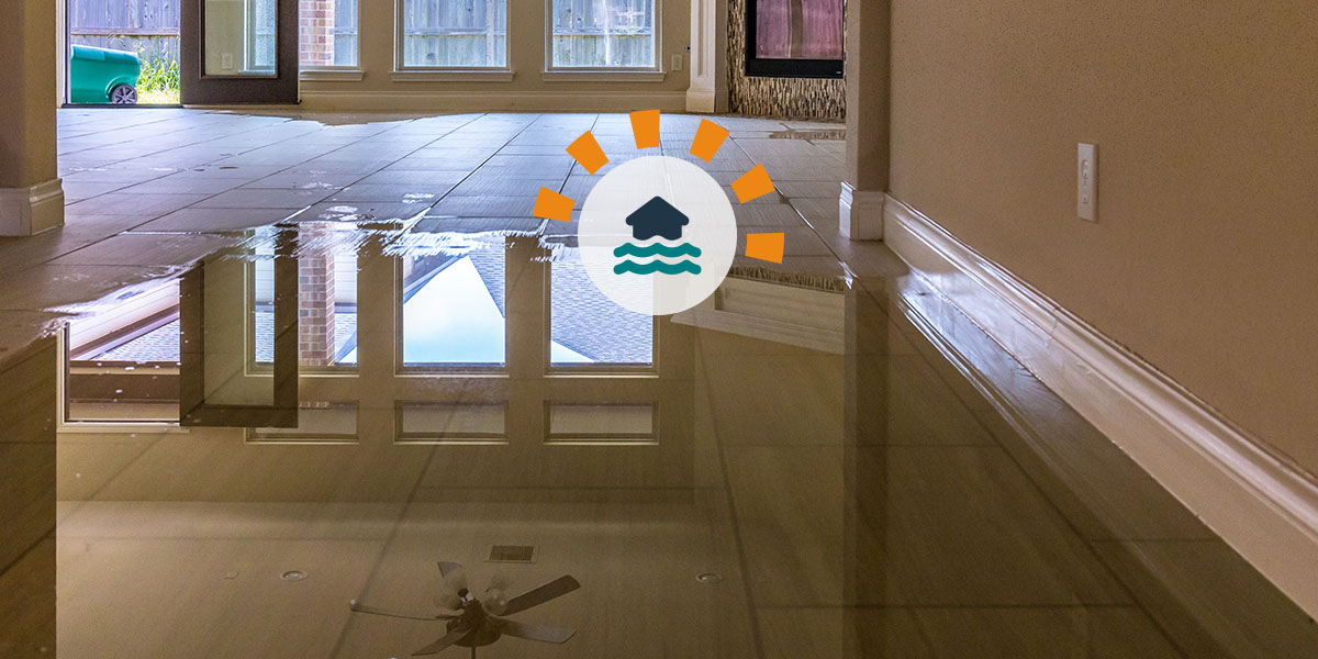 Flooded residential interior with standing water covering tile floors, reflecting ceiling fixtures and doorways