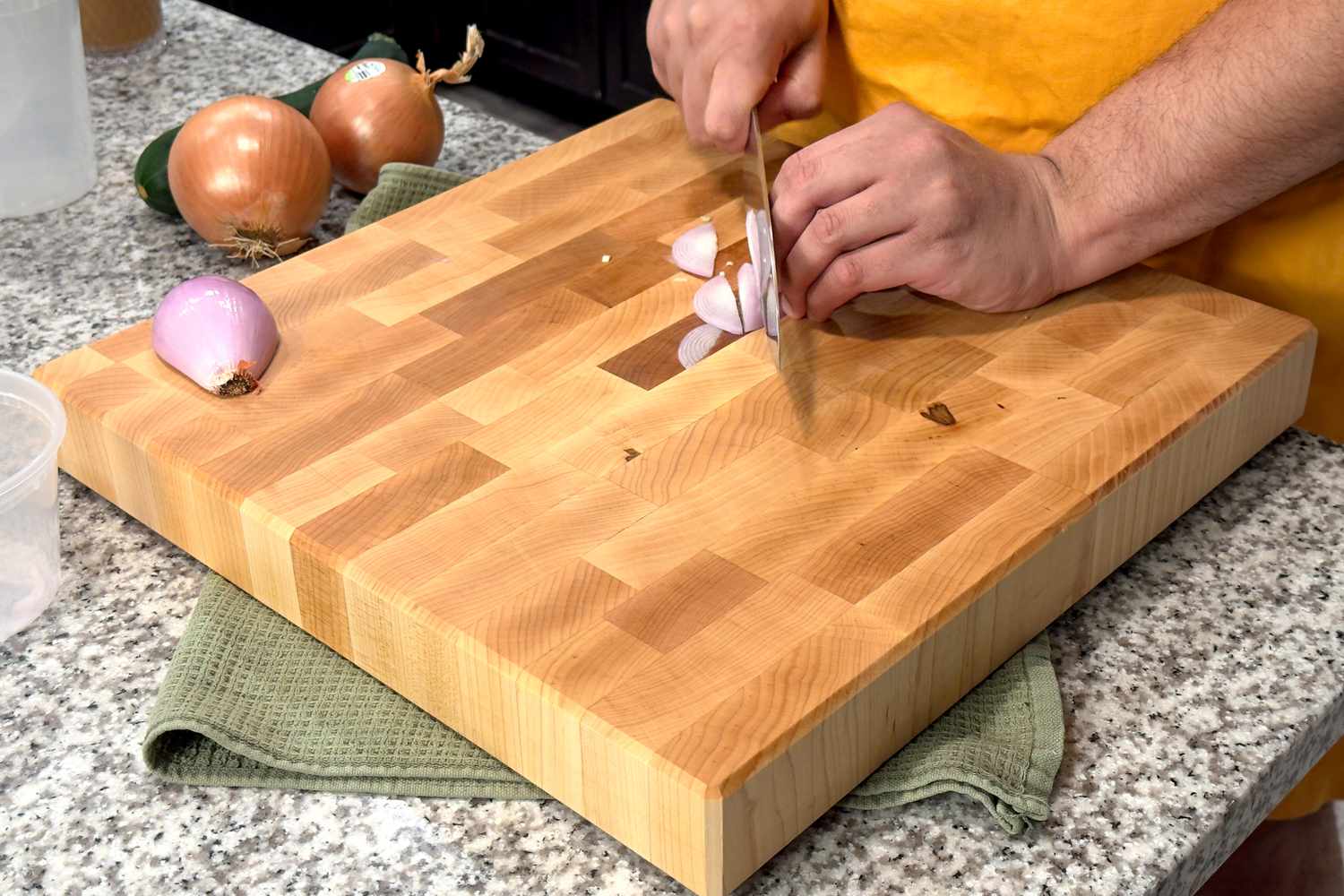 Chef chopping onions on thick end grain maple cutting board showing minimal knife damage for bamboo vs wood cutting board