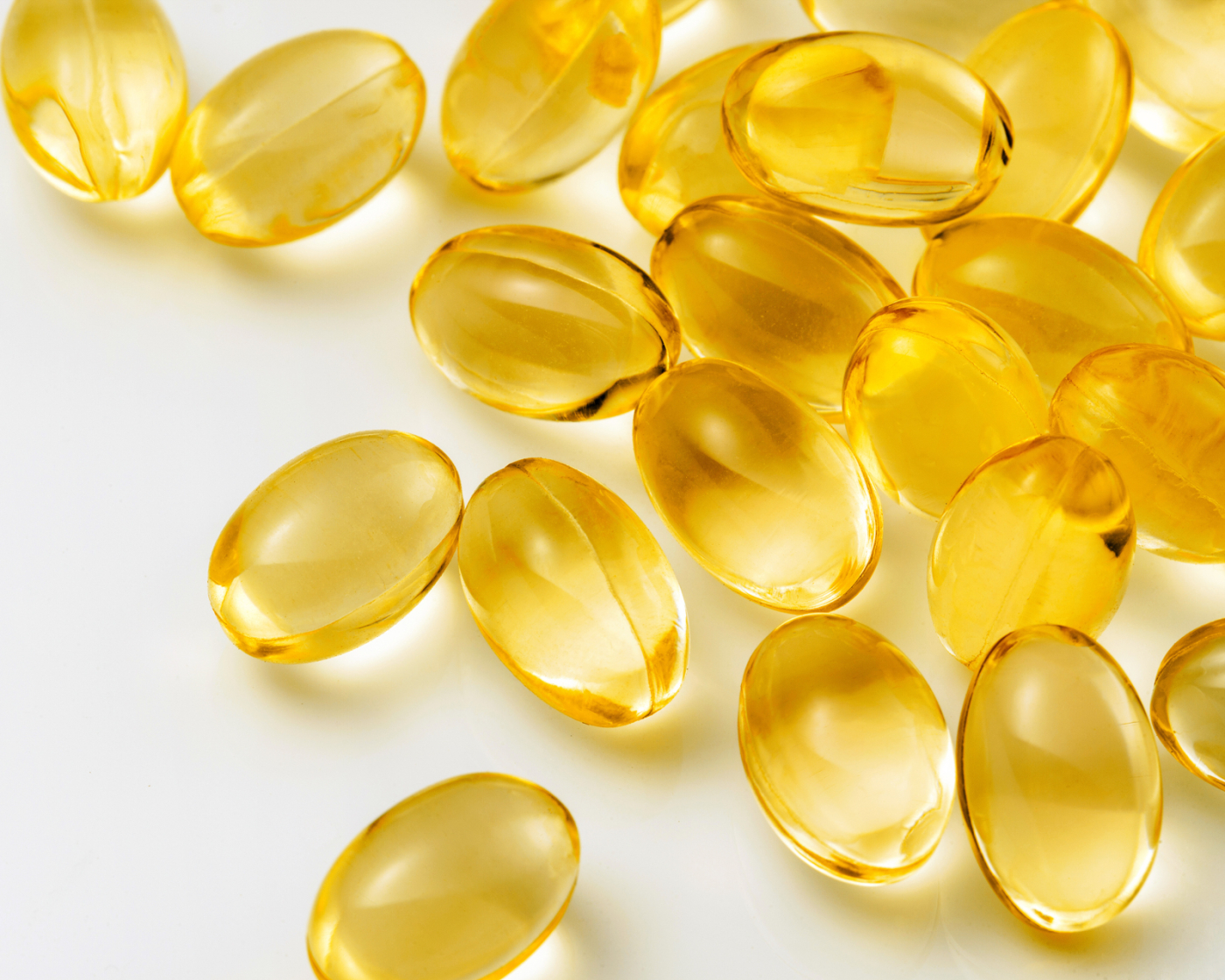 Golden gelatin soft capsules arranged on white background showing pharmaceutical grade quality