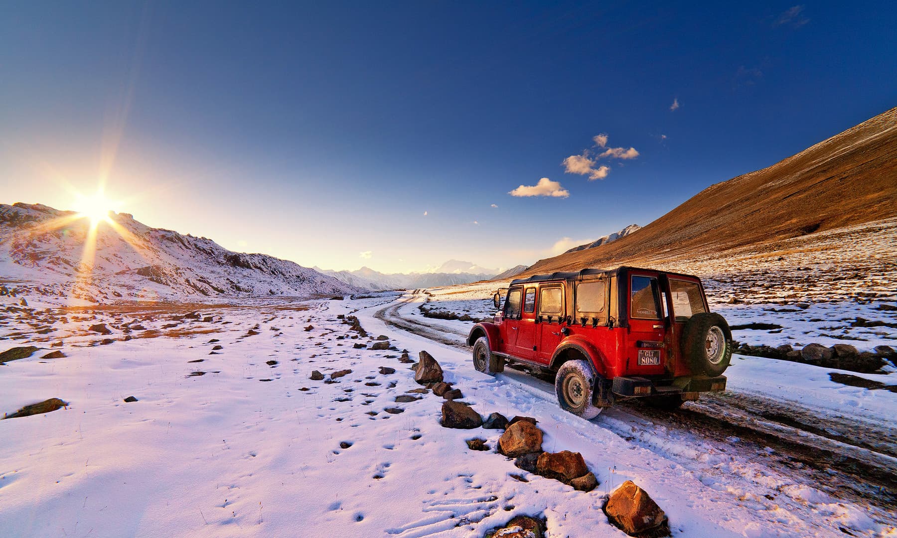 Deosai Plains Jeep Safari Tour with red 4x4 jeep on snow mountain road