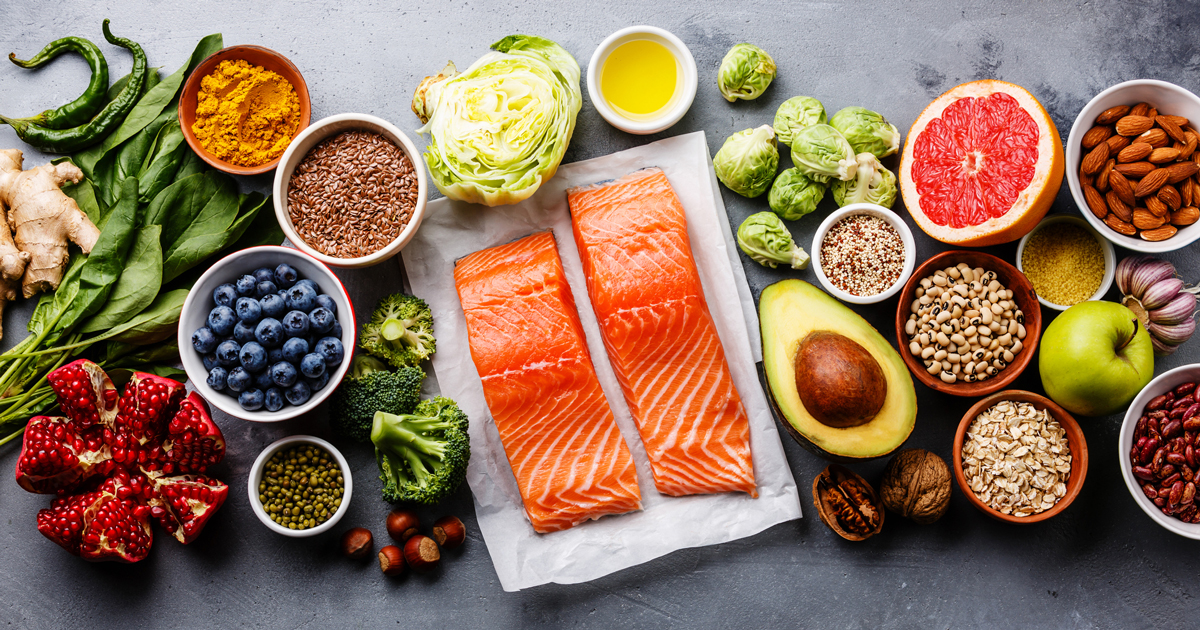 Natural superfoods for everyday wellness with salmon berries and vegetables Colorful array of natural superfoods including salmon, blueberries, avocado, nuts, and vegetables