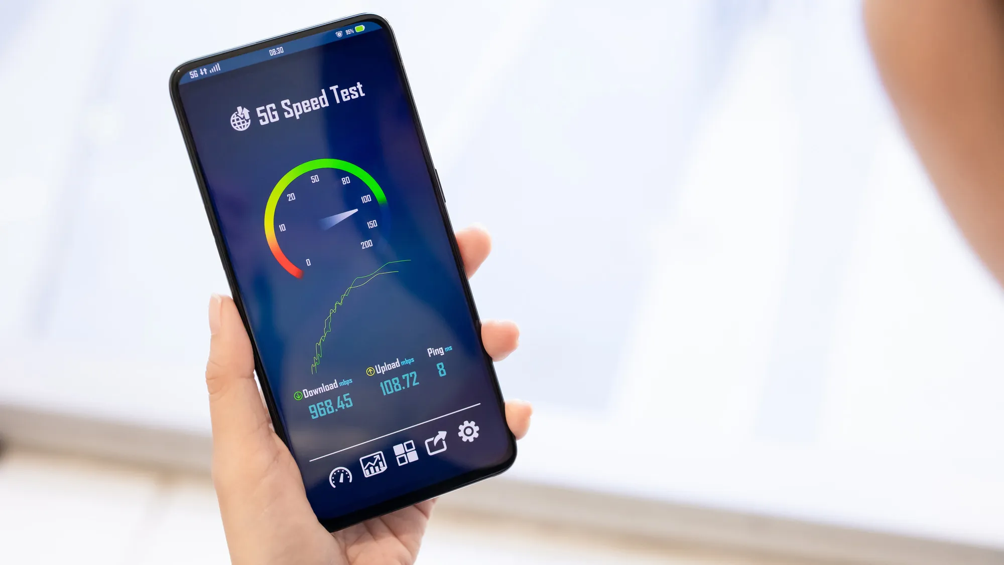Hand holding smartphone running 5G speed test showing fast download speeds
