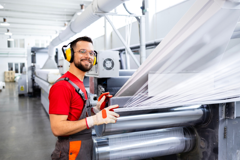 Professional manufacturing engineer inspecting plastic extrusion equipment quality