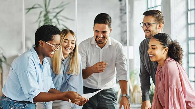 Grupo de funcionários sorrindo e colaborando em ambiente de trabalho moderno