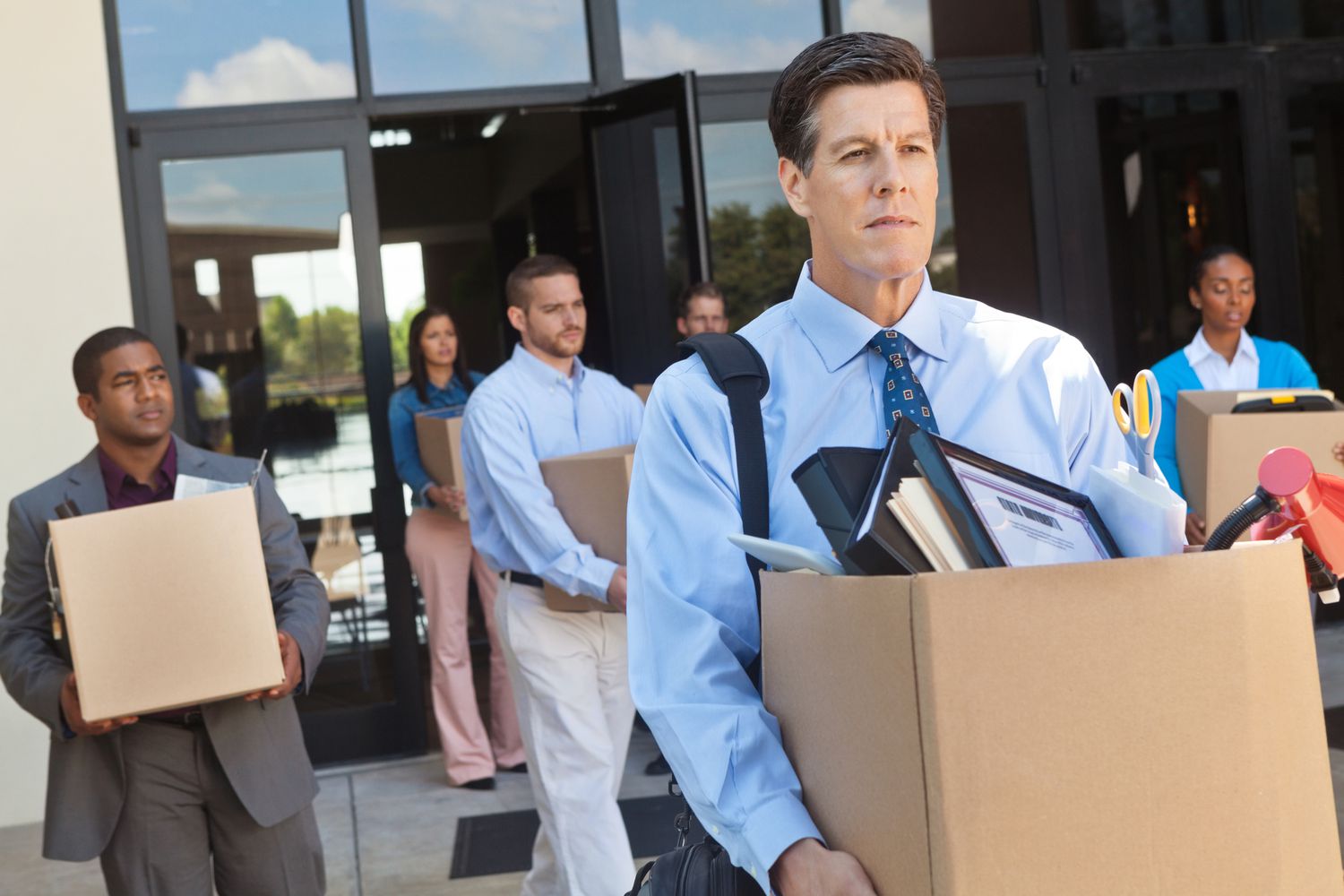 Corporate downsizing - employees leaving office with boxes of personal belongings