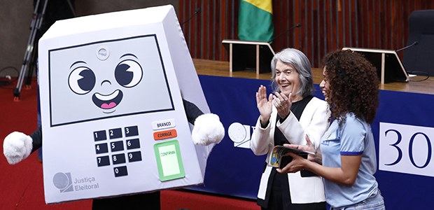 Ministra Cármen Lúcia ao lado do mascote Pilili, representando a urna eletrônica, em celebração dos 30 anos do sistema