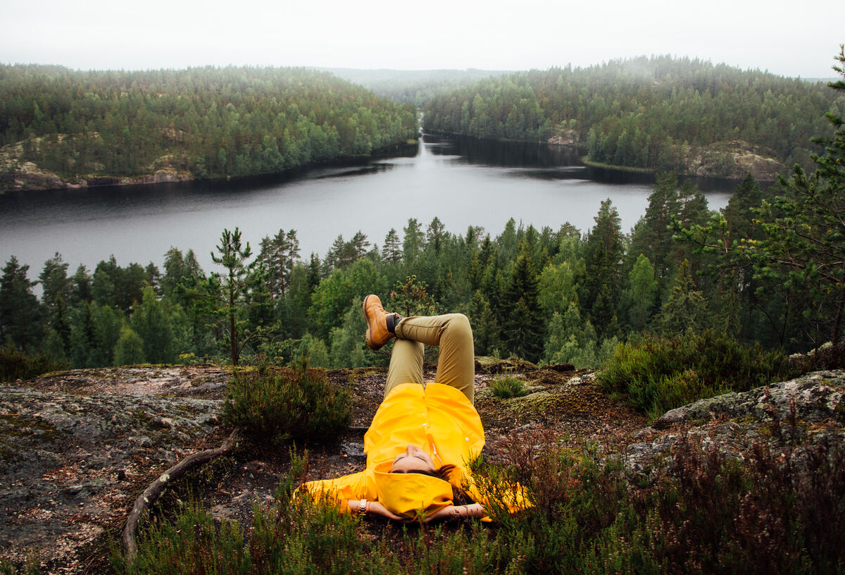 Pessoa relaxando em paisagem natural finlandesa com florestas e lago