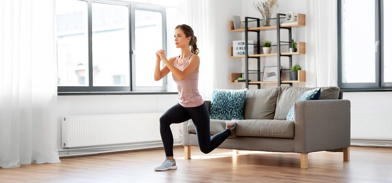 Woman doing a lunge exercise in a bright modern living room during a home workout